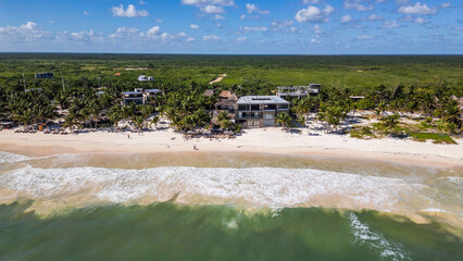 Tulum Beach, Quintana Roo, Mexico, Beach with a large building in the distance. The beach is calm and the water is green
