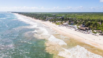 Tulum Beach, Quintana Roo, Mexico, Beautiful beach with a clear blue ocean and a few white buildings in the background. The beach is empty and the water is calm