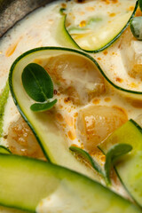 Artful zucchini ribbons swirl around scallops in a velvety sauce, reflecting the skill of a chef at a fine dining restaurant during a sunny afternoon. Each bite promises delight