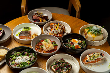 A table filled with an array of beautifully presented dishes, featuring fresh ingredients and vibrant colors, inviting diners to savor each unique creation in a warm atmosphere