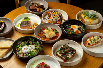 A delightful assortment of colorful dishes fills the table, each showcasing unique ingredients and presentation. Enjoying a feast in a warm atmosphere, friends gather to savor fresh flavors