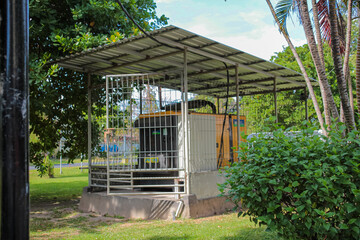 Secured industrial diesel generator enclosed in outdoor utility cage.