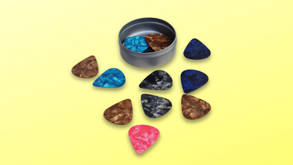 Guitar picks spreading from tin box on yellow