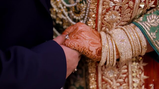 Bride and groom Mehndi holding each others hands during Wedding Photoshoot. Bangles on henna painted hands
