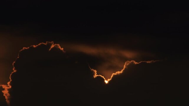 Sun hiding at sunset between clouds. Time Lapse