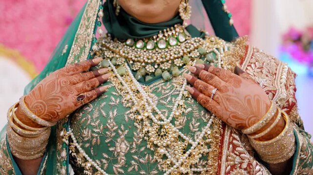 Green and gold colors in the traditional wedding Indian or Pakistan clothes, Close up view of embroidered dress and henna painted hands on it