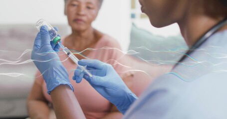 Preparing nurse in blue scrubs and gloves drawing vaccine into syringe at home with stethoscope