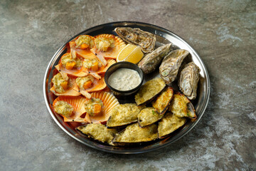 A vibrant seafood platter displays an assortment of delicately prepared scallops, oysters, and savory dips, inviting gourmets to savor these oceanic delights at sunset