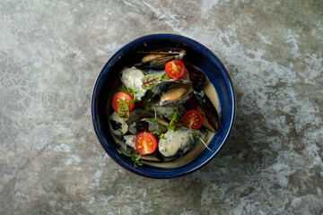 A vibrant bowl filled with seafood, featuring mussels and fresh tomatoes garnished with herbs