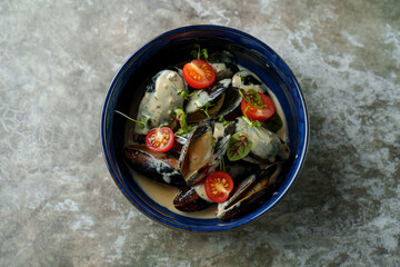 Succulent mussels are nestled in a luscious creamy sauce, topped with fresh cherry tomatoes and vibrant herbs. This delightful dish captures the essence of coastal dining