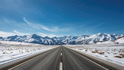 Snow-covered mountains and open landscape from a straight road under a blue sky. Nature and travel, concept. Road trip and adventure. The concept of journey and exploration.