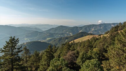Fototapeta premium Mountain landscape with lush green forests and distant mountain ranges under a clear sky