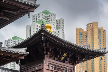 Diamond Hill, Kowloon, Hong Kong : Chi Lin Nunnery pagoda roof and golden finial framed against dense modern residential towers and overcast sky