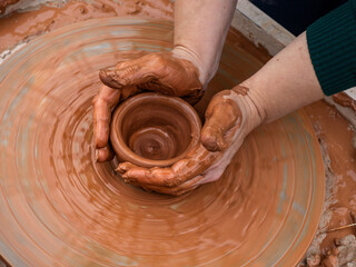 The hands of a female potter at the potter's wheel. Learning the craft of pottery