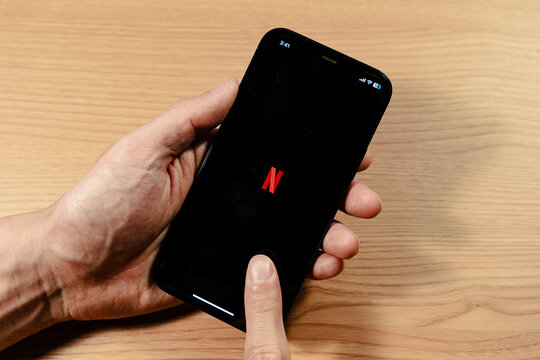 Hand holding smartphone displaying NETFLIX application startup screen - Seoul, South Korea - November 23 2025