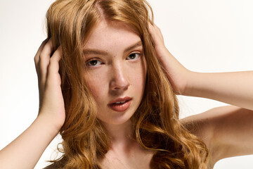 Naklejka premium Radiant redhead woman showcases natural beauty in serene white studio setting