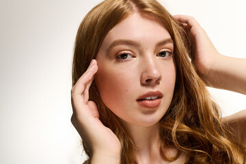 Fototapeta premium Stunning redhead woman showcases natural beauty in a serene white studio setting