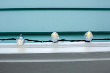 holiday christmas lights hang on side of blue house in winter