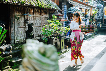 Balinese Woman Carrying Traditional Offering Box in Village Alley
