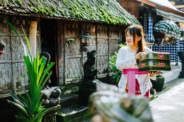 Balinese Woman Carrying Traditional Offering Box in Village Alley