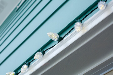 holiday christmas lights hang on side of blue house in winter