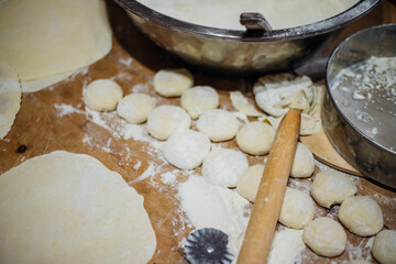 Close-up of an elderly woman's female hands rolling out dough with a wooden rolling pin. Making homemade pies and chebureks.