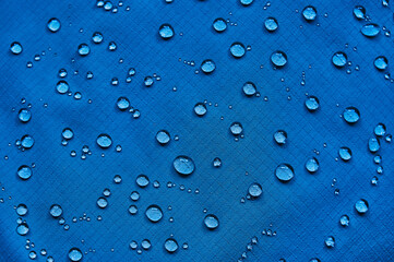 Water drops on waterproof membrane fabric. Detail view of texture of blue waterproof cloth.