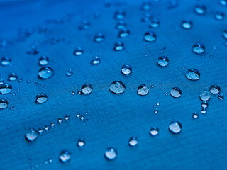 Water drops on waterproof membrane fabric. Detail view of texture of blue waterproof cloth.