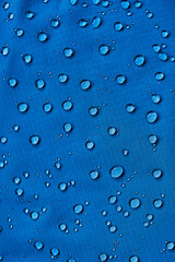 Water drops on waterproof membrane fabric. Detail view of texture of blue waterproof cloth.