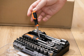 A hand precisely selects an orange-handled screwdriver from a complete comprehensive repair tool kit, perfect for efficient furniture assembly and home improvement tasks