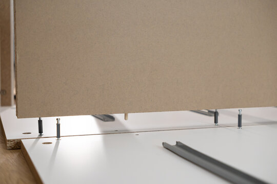 Assembling flat-pack furniture components, revealing detailed connections with dowel pins and cam lock fittings for a home improvement project