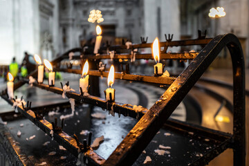 Detailed close up of burning prayer candles on a metal stand