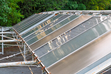 Old, worn flat plate solar collectors mounted on a rusty metal frame
