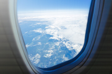 Scenic aerial view from airplane window over clouds and landscape