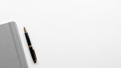 Minimalist flat lay image of a fountain pen and a grey notebook on a white background
