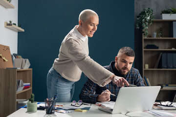 Colleagues collaborating on business project using laptop in office