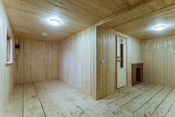 compact woodpaneled space with door and light, clean pine floors and walls suggest flexible living or guest room, quiet rustic mood and staging for interior design or cleaning