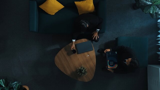 Top view of business people analyze stock market investment data by using laptop and financial graph while smart businessman walk out of the meeting room and return to seat. Time lapse. Directorate. - Powered by Adobe