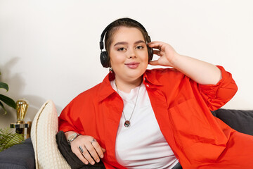 Beautiful plus size woman relaxing at home while listening to music on headphones