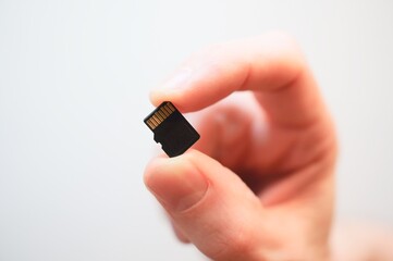 hand with flash memory. hand holding micro sd card. Caucasian hand holding a microSD memory card.