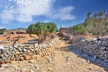 A dirt path leading between  with stone walls in Kalydon (Spinalonga) peninsula near Elounda town of Crete island in Greece,