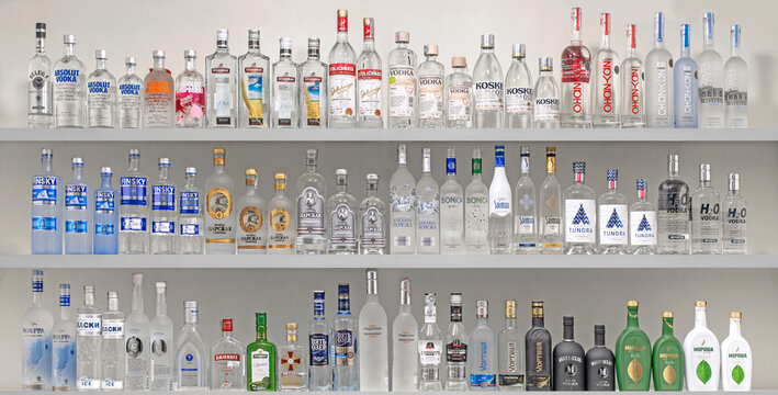 A shelf full of vodkabottles, including vodka, gin, and tequila
