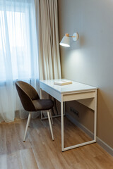minimalist work area, hotel workspace with lighting and seating, quiet hotel corner arranged for professional tasks, serene hotel nook equipped for business activities and productivity