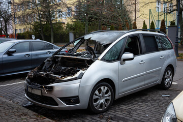 Burnt passenger car standing on the city street. Vehicle with interior largely burnt out.