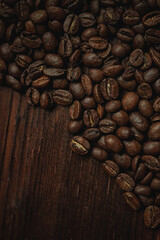 Roasted arabica coffee beans scattered on dark rustic wooden surface, creating a rich texture and aroma background