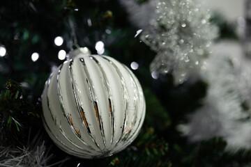 White and silver bauble hanging on Christmas tree