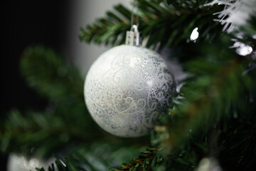 Silver Christmas bauble decorating a green fir tree branch