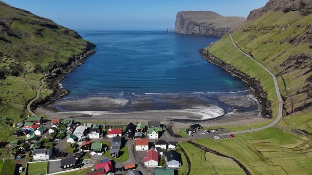 Drone flying forward above Faroe Island small village tj&oslash;rnuv&iacute;k on the beach towards the ocean