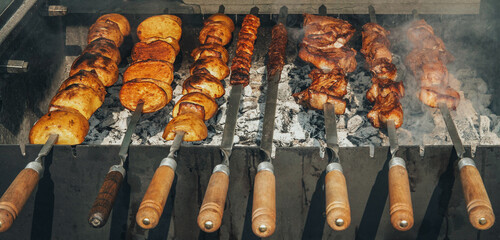 A grill with skewers of meat and potatoes on it