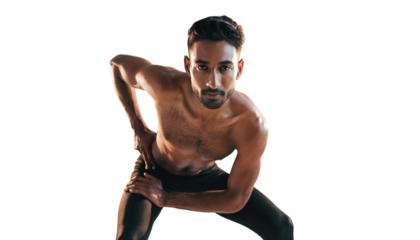 Muscular man striking an athletic pose, looking at camera during an indoor fitness training session.